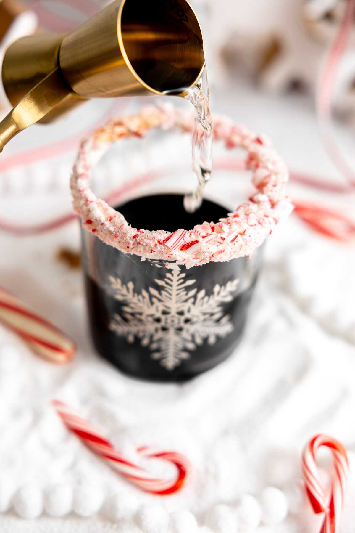 Peppermint vodka being poured into the prepared glass. 