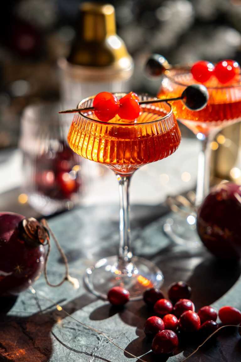 Christmas cheer cocktails in coupe glasses in front of a Christmas tree.