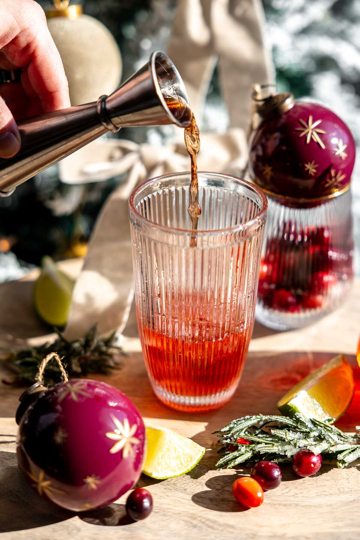 Cranberry juice being poured into a cocktail shaker. 