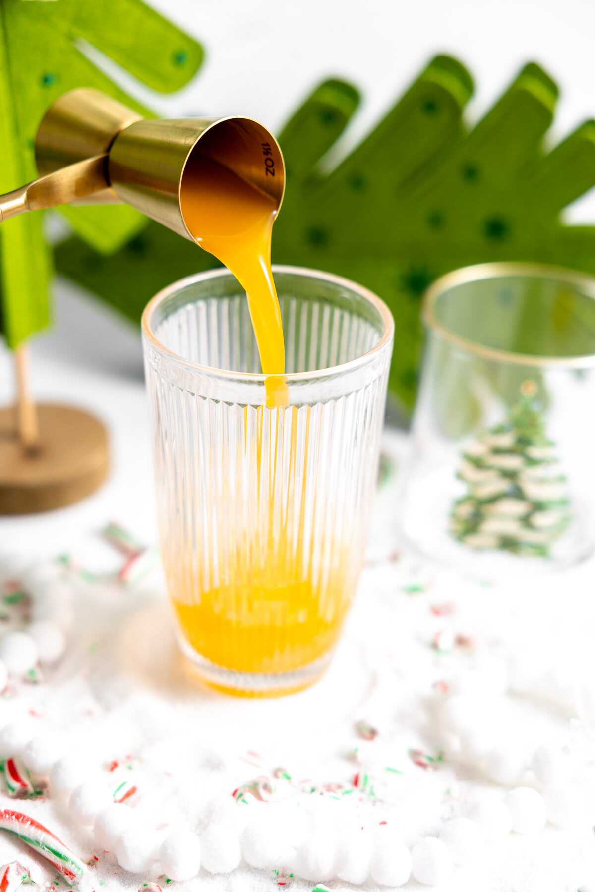 Mango juice being poured into a cocktail shaker. 