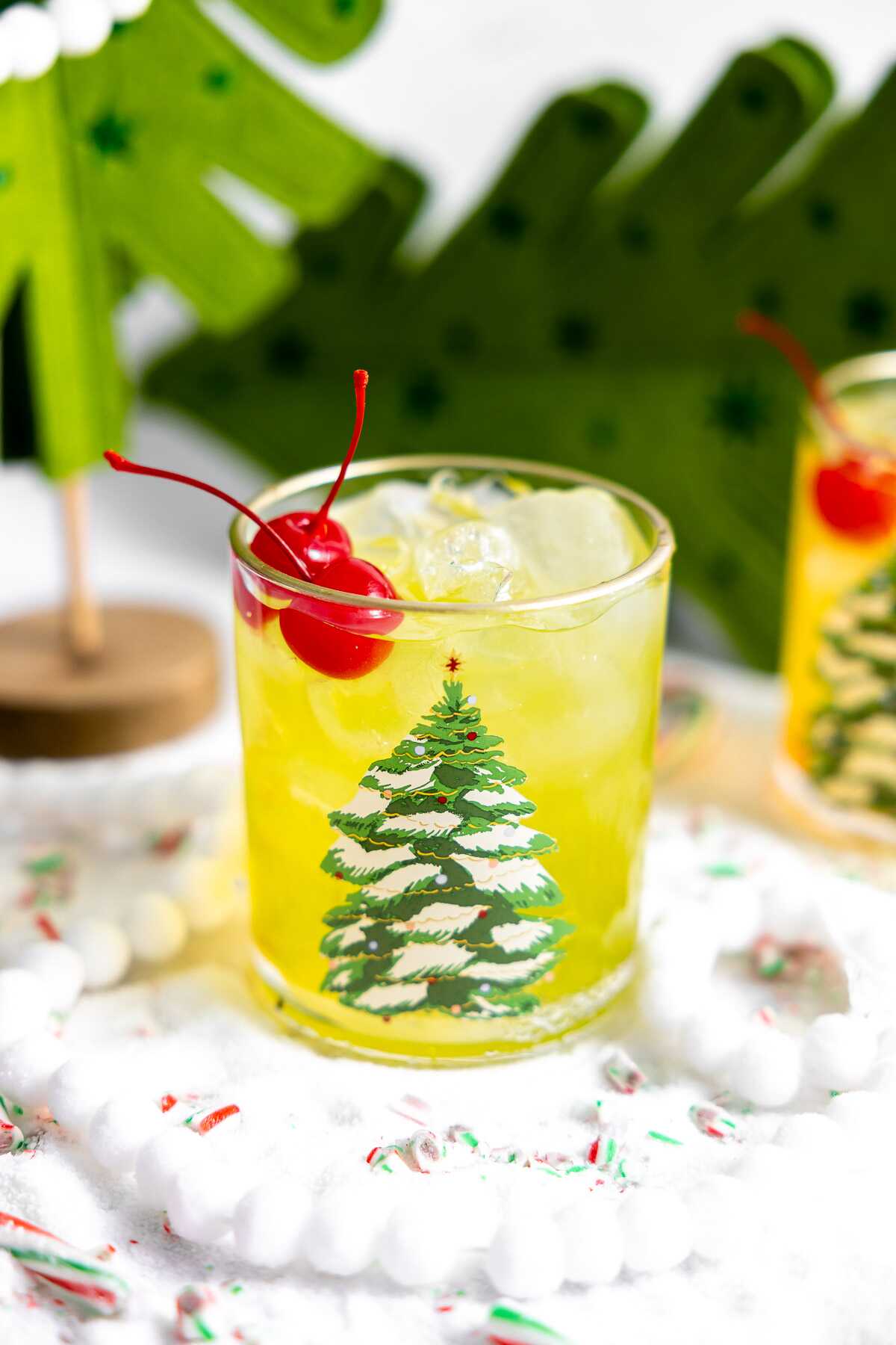 The Grinch cocktail in a festive glass garnished with cherries. 