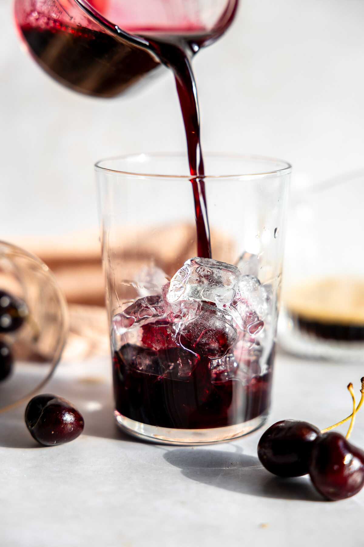 Cherry vanilla syrup being poured into a glass of ice.