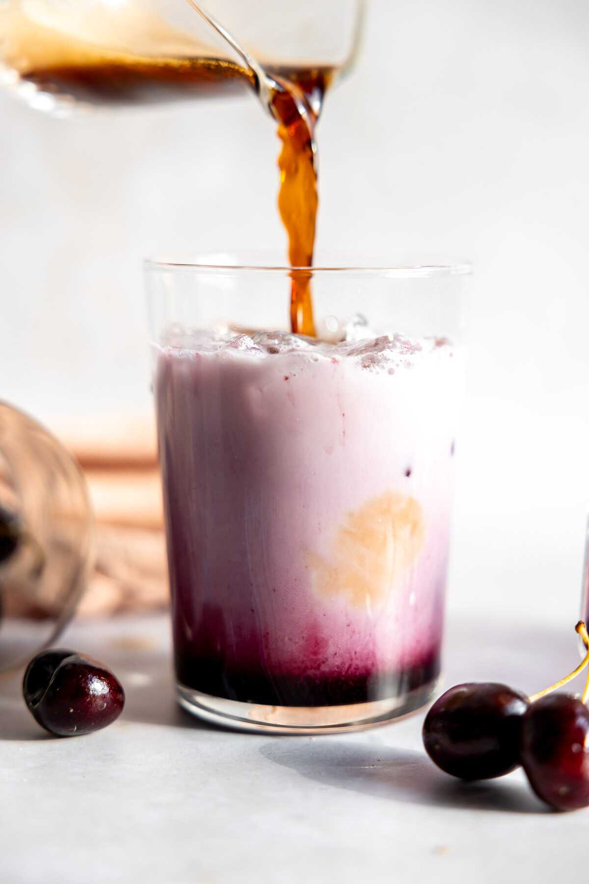 Espresso being poured into the coconut milk and cherry syrup.