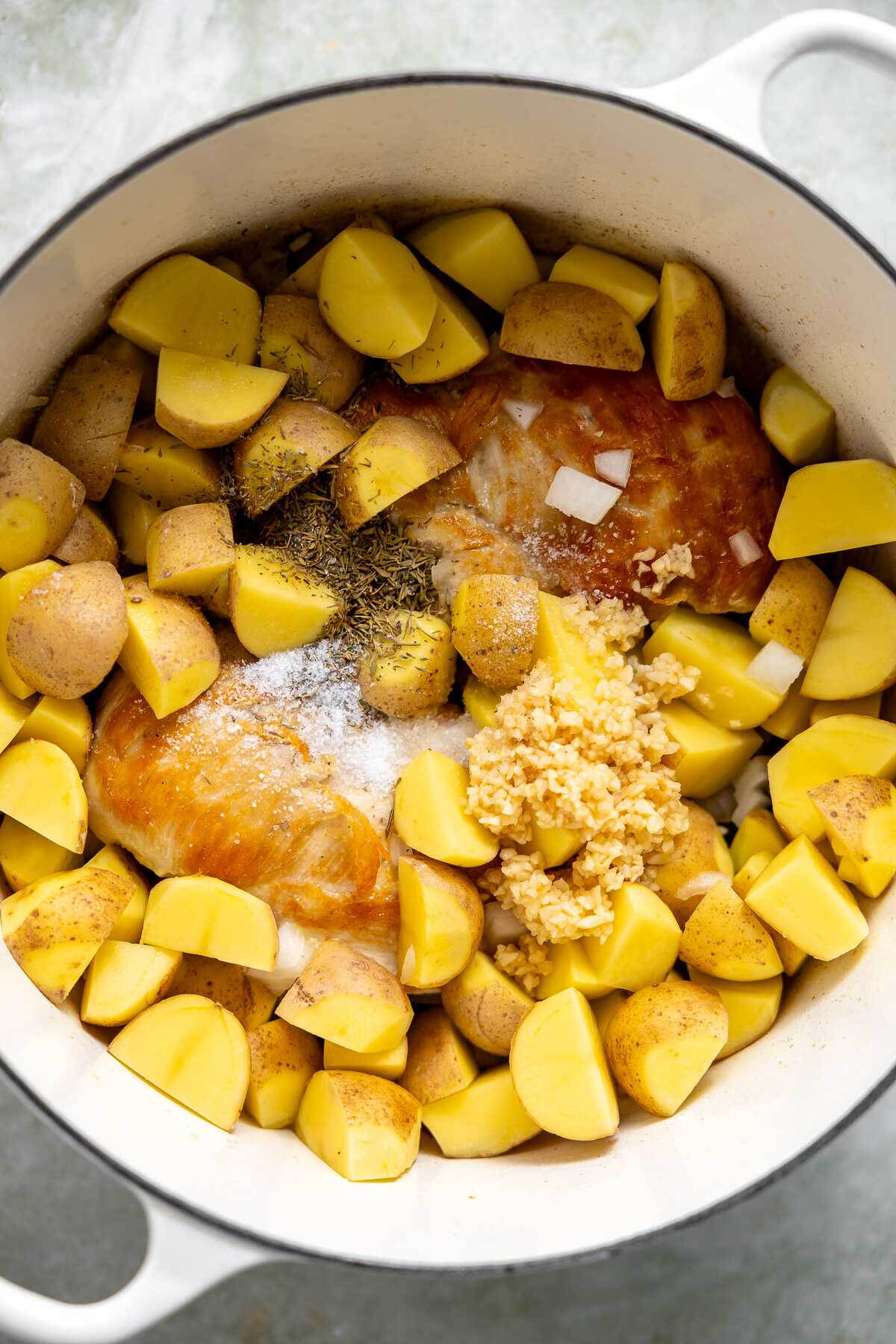 Seared chicken in a pot with onions and potatoes. 