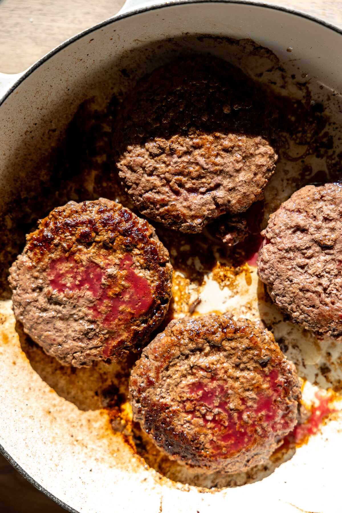 Seared hamburger patties in a skillet.