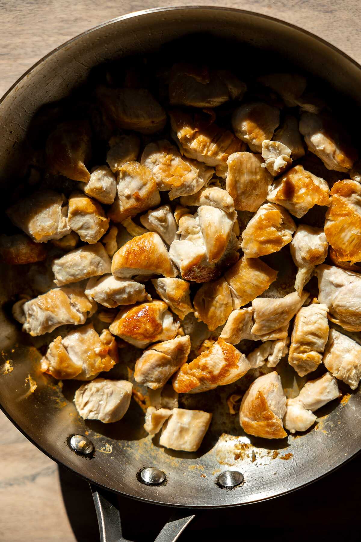 Seared cubes of chicken in a skillet.